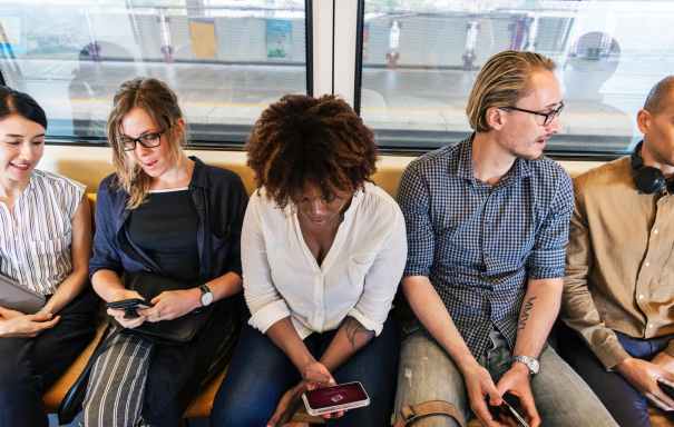 woman sitting holding smartphone between two men and two women